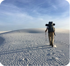Traveller hiking across white sand dunes